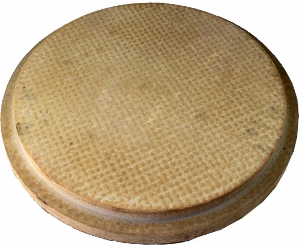 Runder, flacher Stein mit einer genoppten Oberfläche, geeignet für den Brennraum. Produkt von Wolf, verwendet in spezifischen Heizsystemen.